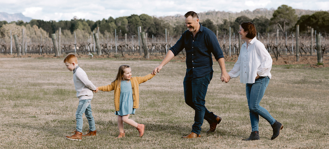 A family holdiing hands while walking in the vineyard 